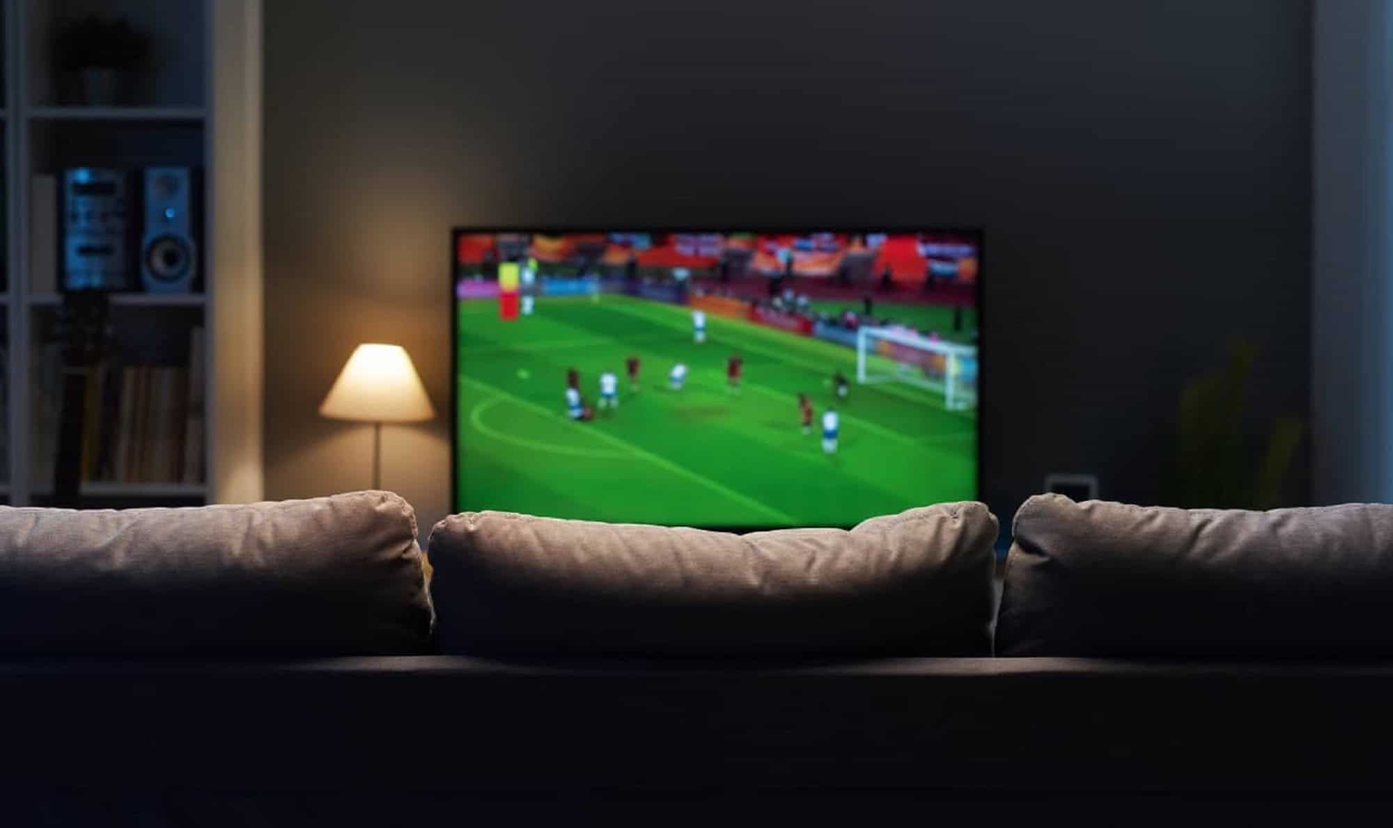 Tela de celular mostrando um jogo de futebol sendo transmitido via streaming, com o logo do Olhar Digital ao fundo.