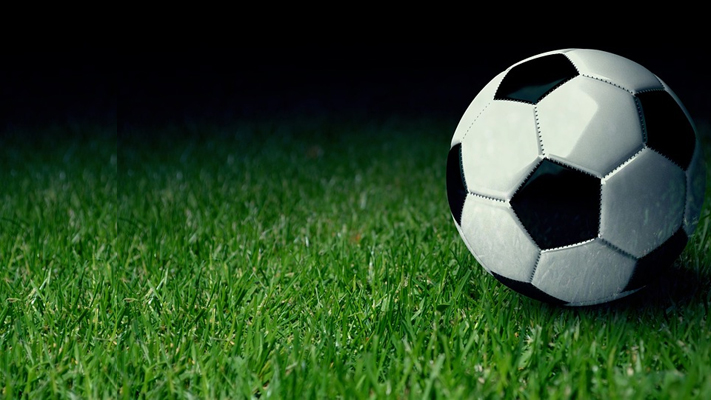 Um estádio de futebol moderno com painéis de LED exibindo logotipos de empresas de apostas esportivas durante um jogo.