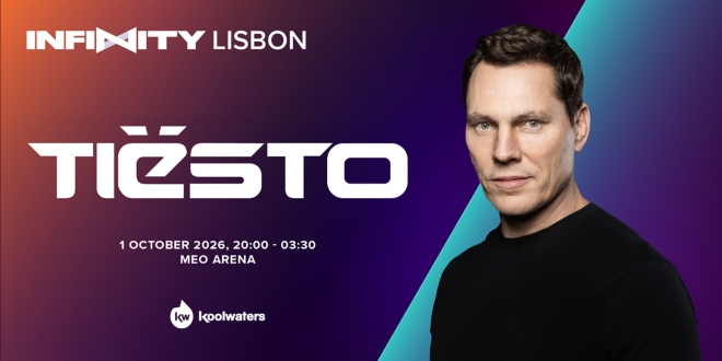 Tiësto se apresentando em um palco de festival de música eletrônica com luzes vibrantes.