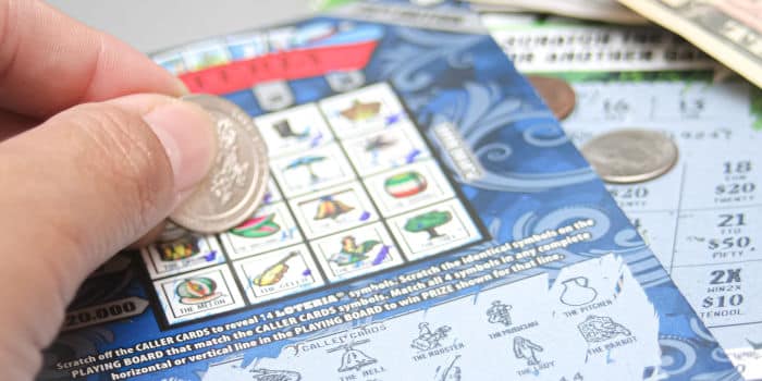 Homem sorridente de 27 anos segurando um bilhete de loteria premiado de US$ 2 milhões.
