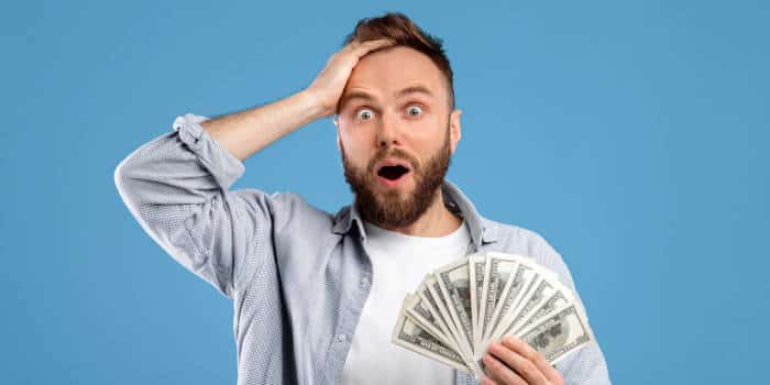 Homem anônimo de Illinois sorrindo e segurando um cheque simbólico gigante de US$ 1,3 milhão da loteria.
