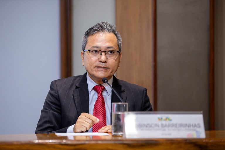 Um influenciador digital usando um smartphone, com o logo da Receita Federal do Brasil discretamente ao fundo, simbolizando a nova medida de taxação.