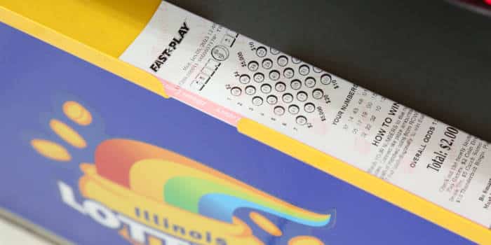 Apostadora anônima conhecida como Lady Luck segura cheque simbólico de US$ 2 milhões na sede da loteria de Illinois